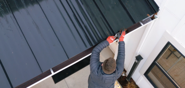 Man cleaning the gutters of his modern farmhouse style home.