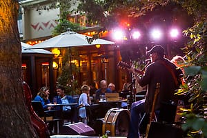 This image is of a man playing guitar on a stage outside at the McMenamins Anderson School in Bothell, Washington. A fun place to go if you're looking for things to do in Bothell. 